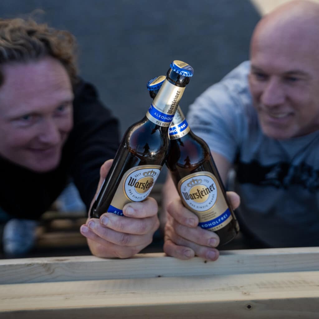 Twee mannen die proosten met twee flessen warsteiner alcoholvrij