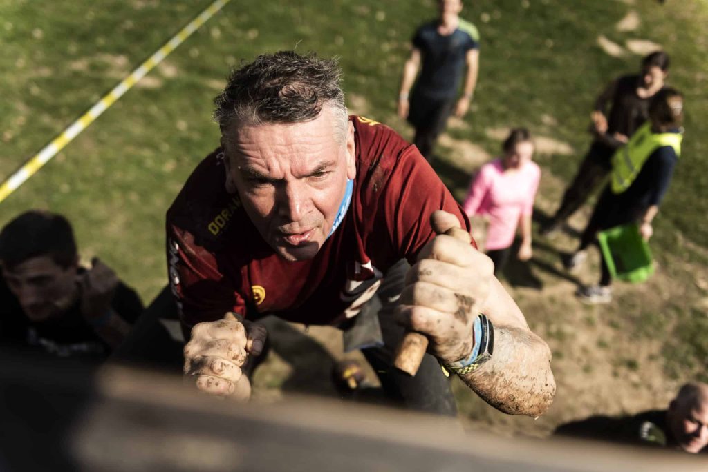 Man die omhoog klimt tijdens strong viking (foto bij spierpijn voorkomen na obstacle run spierpijn verminderen sporten spierpijn)