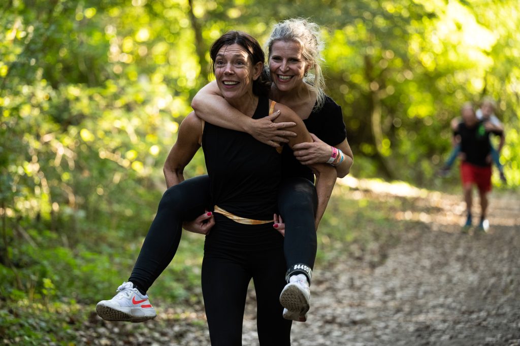 Vrouw die een andere vrouw op de rug tilt. (foto bij Blaren voorkomen, blaren hardlopen vermeiden)